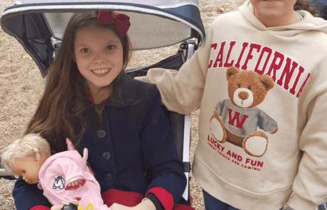 Carolina, dans sa poussette adaptée et une poupée dans les bras, au parc avec sa meilleure amie Patricia.