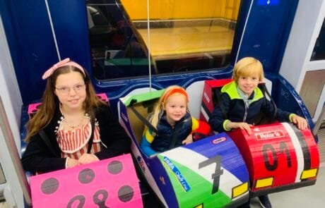 Carolina et ses frères et sœurs prennent le métro avec leurs déguisements d’autos tamponneuses, en route pour le concours.