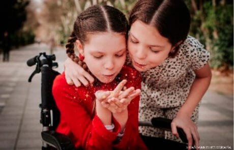 Carolina, en fauteuil roulant, et sa sœur Isabel soufflent ensemble une poignée de paillettes.