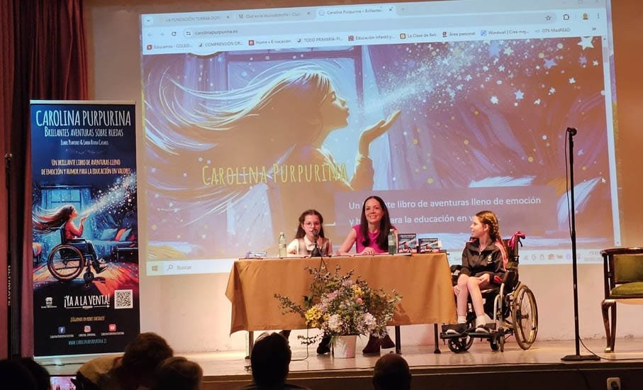Présentation dans une salle : la couverture projetée, le kakémono du livre et une fille en fauteuil roulant près de la table.