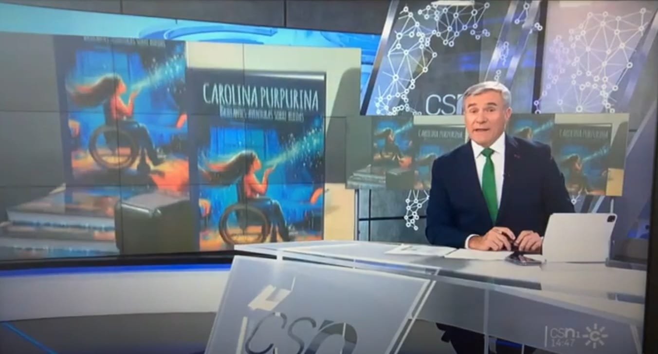 Un présentateur de journal télévisé sur le plateau, la couverture de « Carolina Purpurina » sur les écrans du décor.