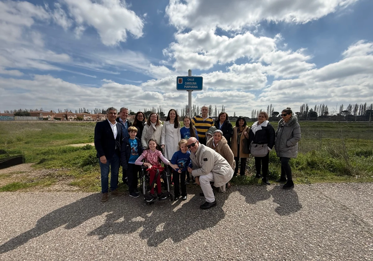 Un groupe pose sous la plaque de la calle Carolina Purpurina ; au centre, une fille en fauteuil roulant.