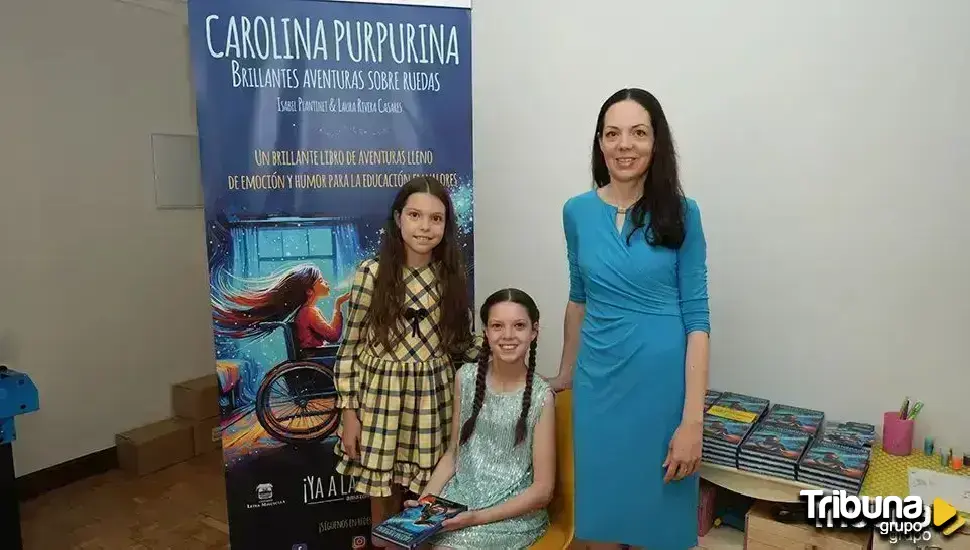 Deux filles et une femme posent devant le kakémono de « Carolina Purpurina » ; à droite, des piles d’exemplaires sur une table.