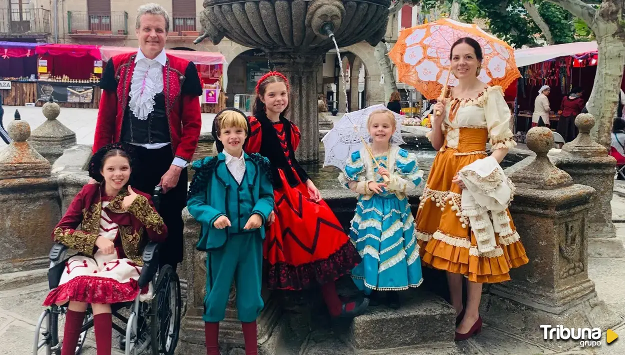 Près d’une fontaine en pierre, un groupe en costumes goyesques avec ombrelles ; une fille en fauteuil roulant lève le pouce.