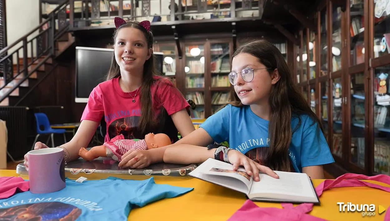 Carolina et Isabel dans une bibliothèque, le livre ouvert, une poupée et des t-shirts Carolina Purpurina.