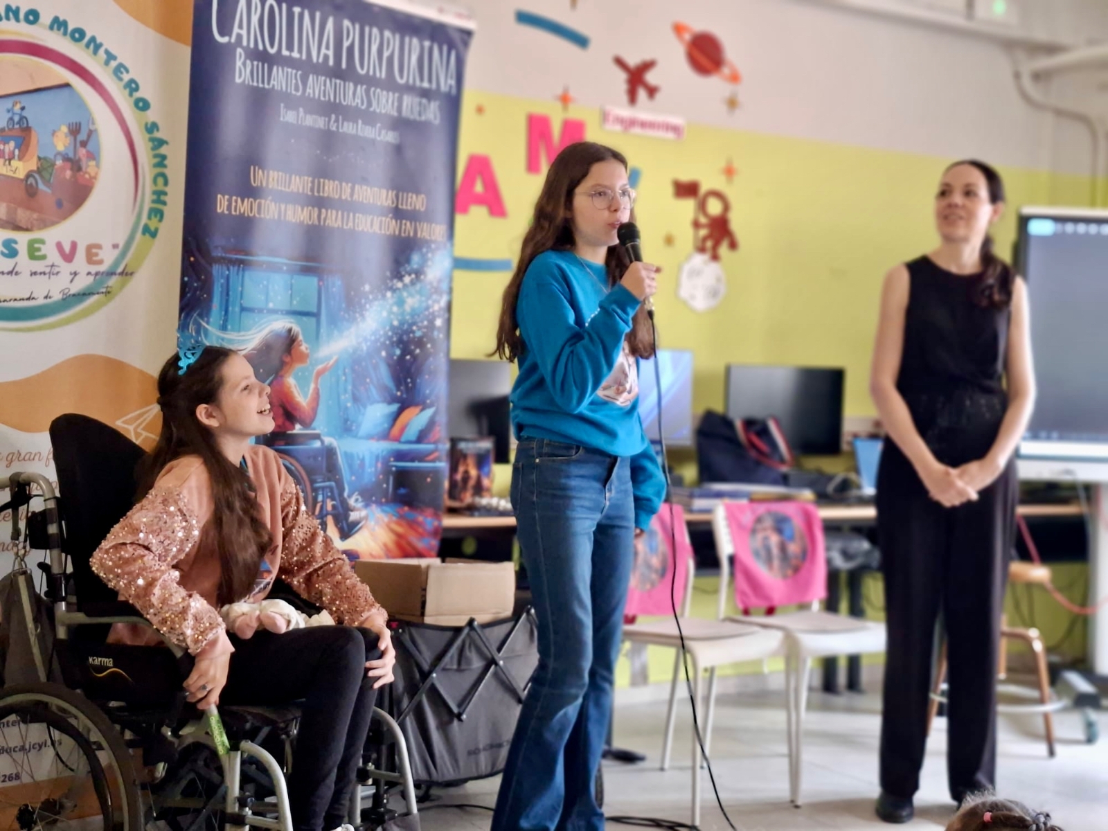 Isabel prend le micro pendant la rencontre scolaire, Carolina et Laura à ses côtés.