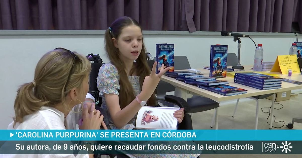 Reportage de Canal Sur à Cordoue : une fillette assise, livre ouvert, parle avec une femme ; derrière, la table chargée d’exemplaires du livre.