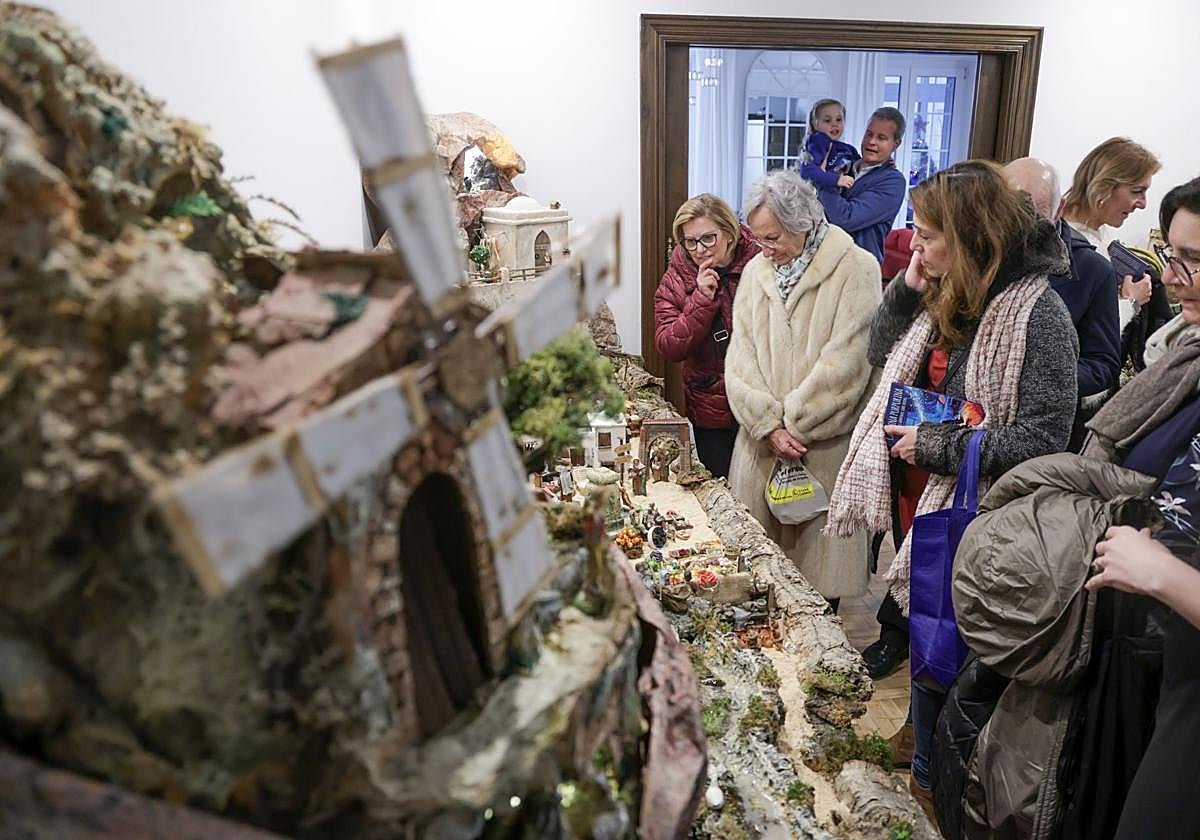 Des visiteurs contemplent la grande crèche de la famille, un moulin au premier plan, pendant la journée portes ouvertes.