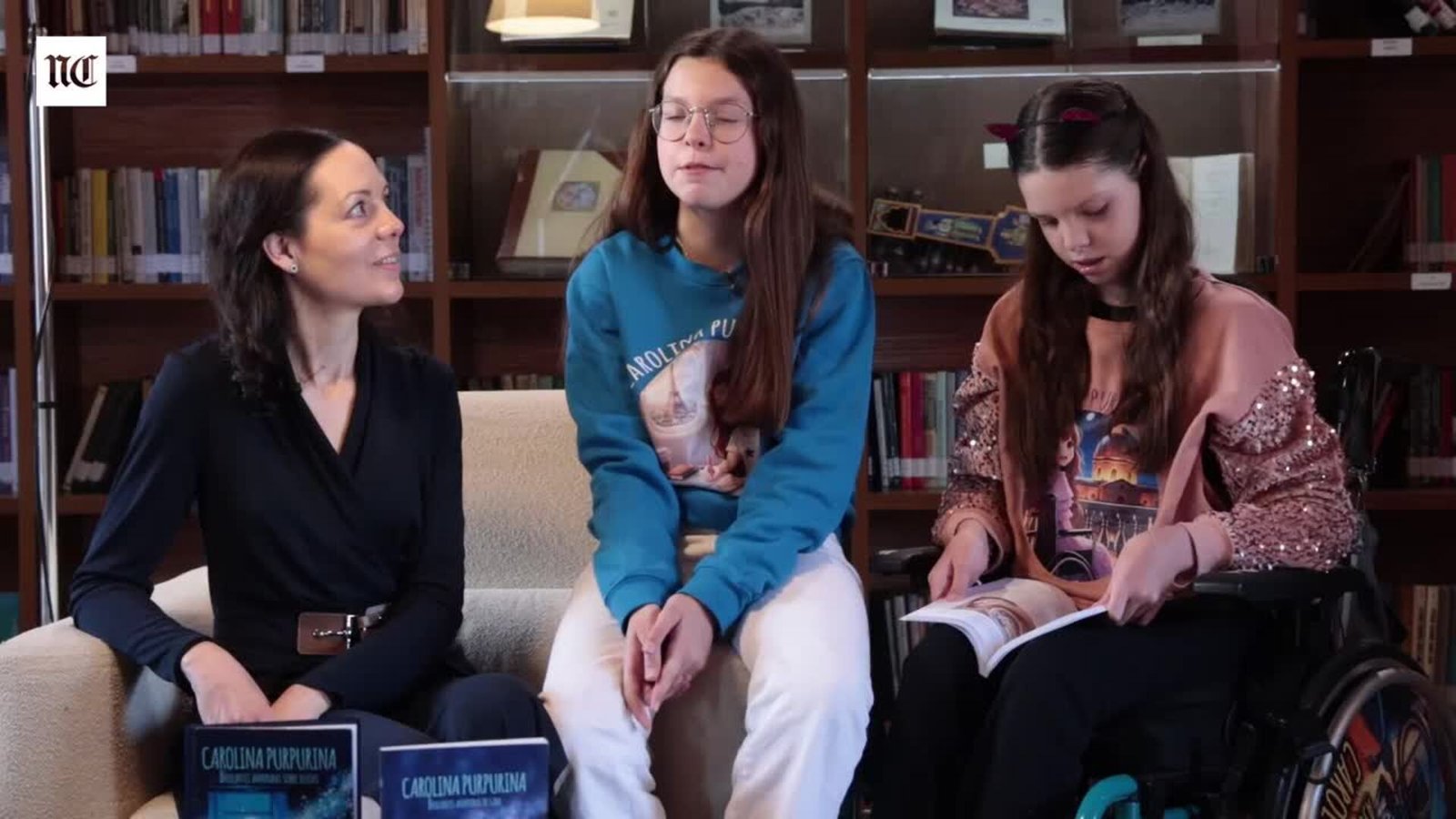Entretien sur le troisième livre : Laura et Isabel, derrière deux livres Carolina Purpurina, et Carolina, dans son fauteuil, qui en feuillette un.